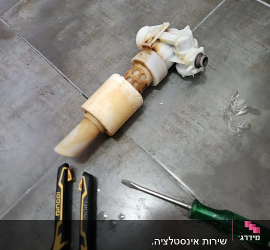 חלקי צנרת וכלי עבודה על רצפה אפורה